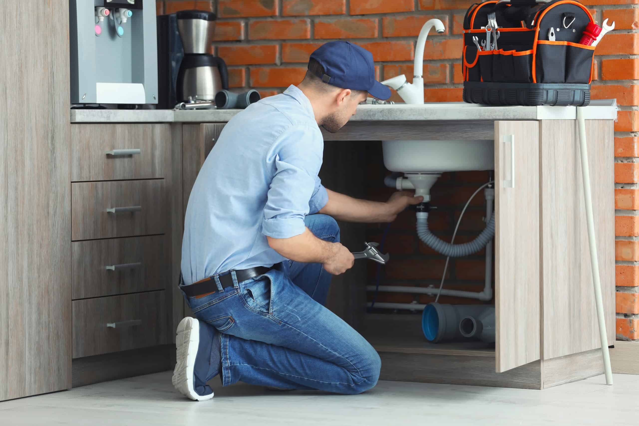 Plumber performing a repair under a kitchen sink as part of HD Drain Cleaning's plumbing services in Ormond Beach, FL