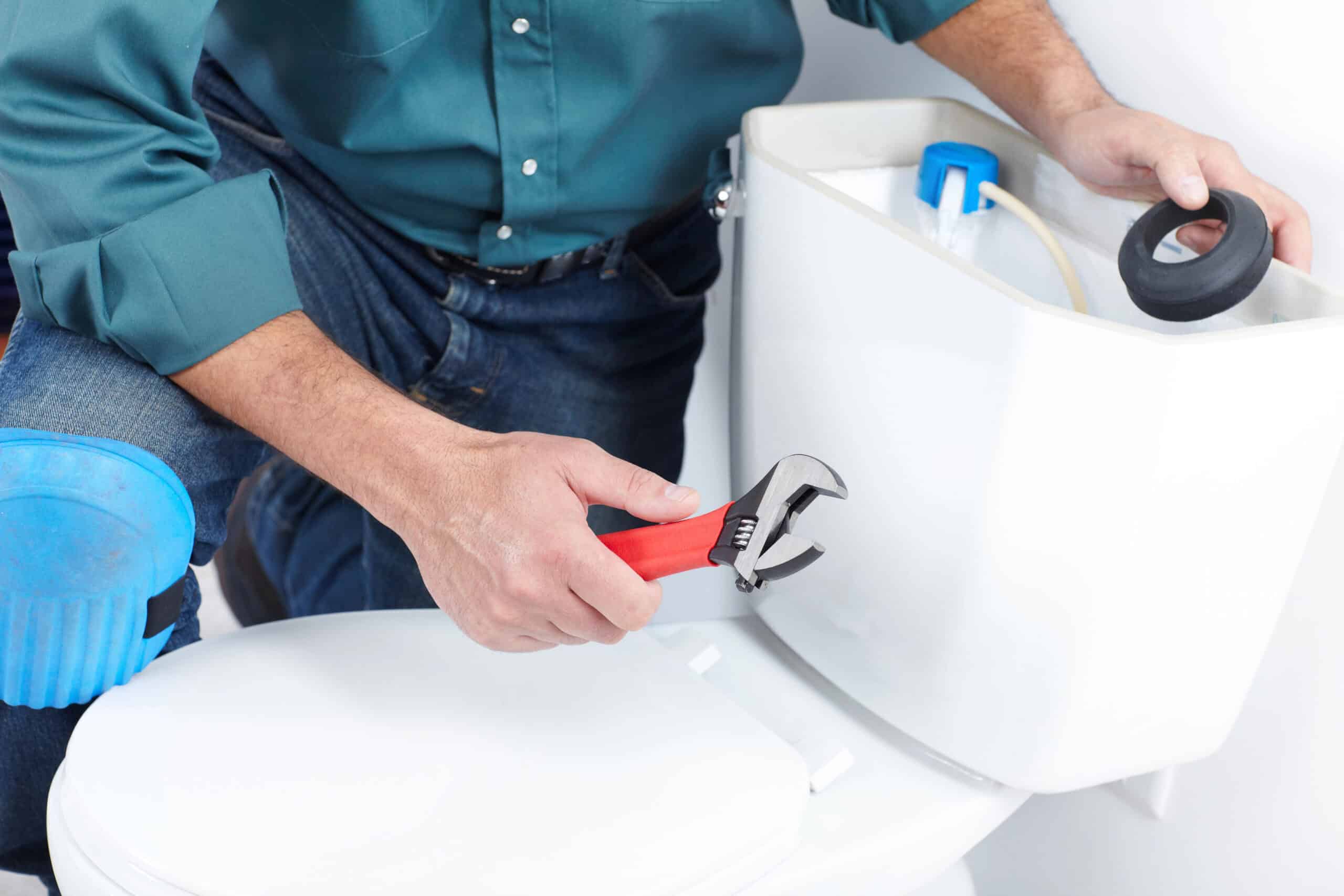 Plumber repairing the inside of a toilet tank using professional tools, provided by HD Drain Cleaning’s toilet repair services in Ormond Beach, FL