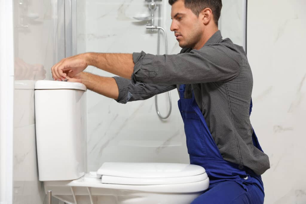 Plumber repairing a toilet tank during HD Drain Cleaning's comprehensive plumbing services