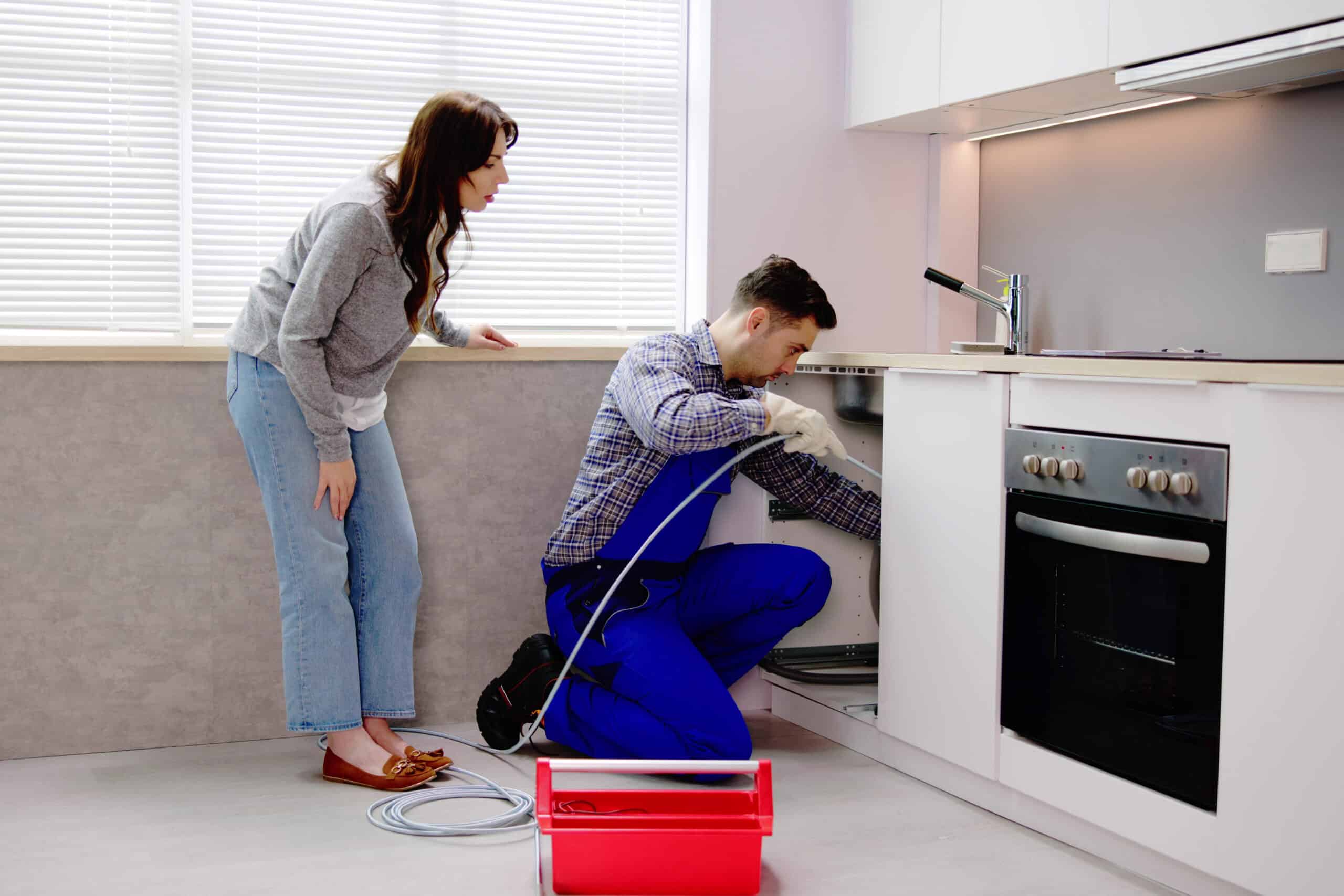 Plumber performing kitchen drain cleaning while homeowner watches, part of HD Drain Cleaning’s professional plumbing services in Holly Hill, FL.