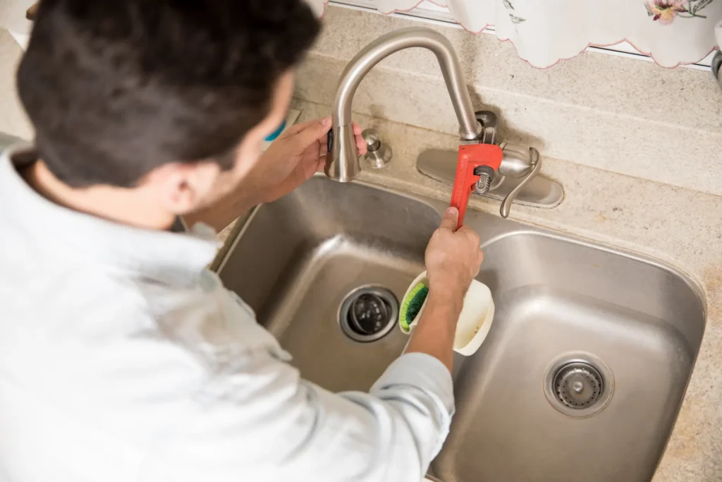 a man using a wrench to repair a faucet